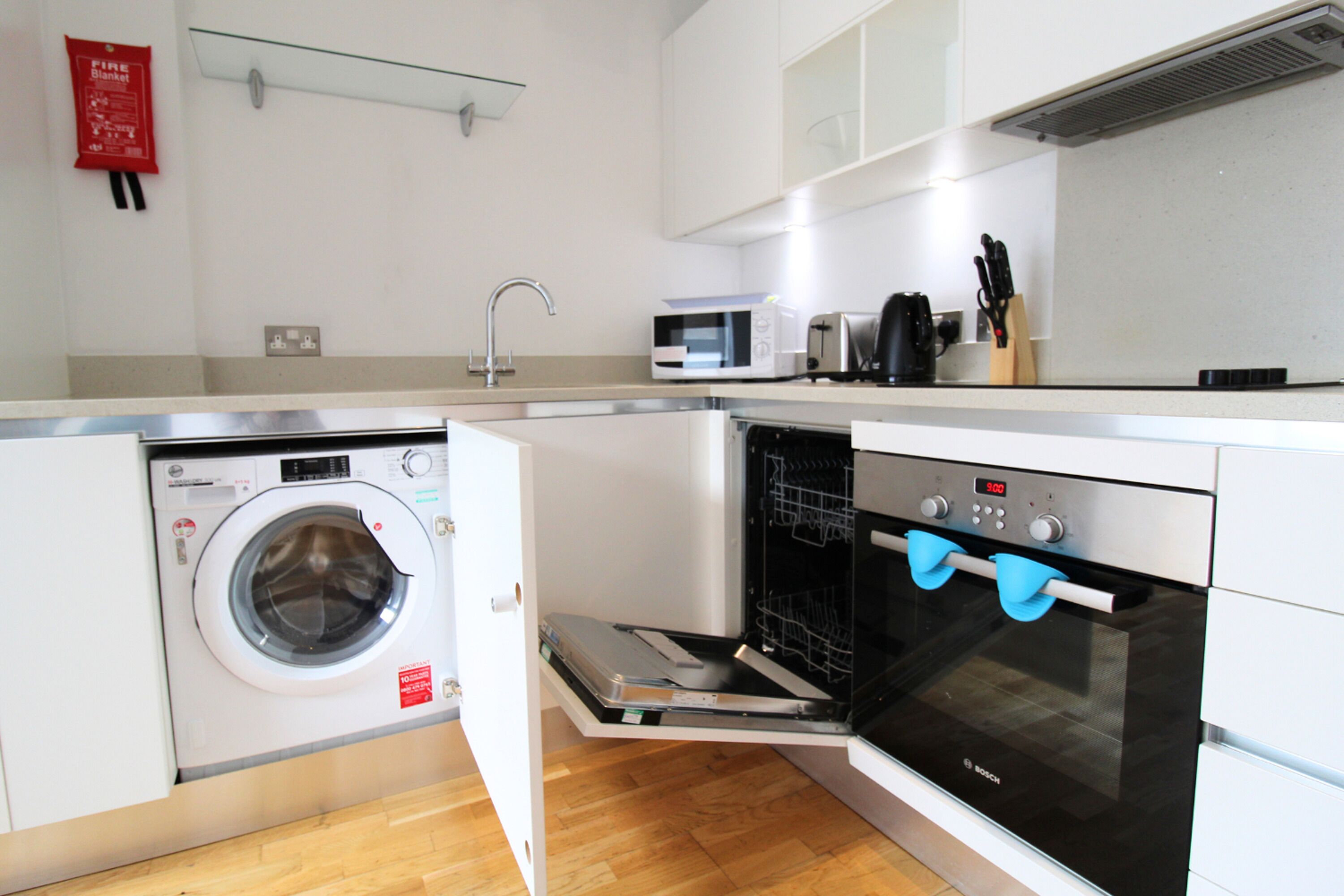 A compact kitchen with a built-in washing machine, a microwave, and an oven.
