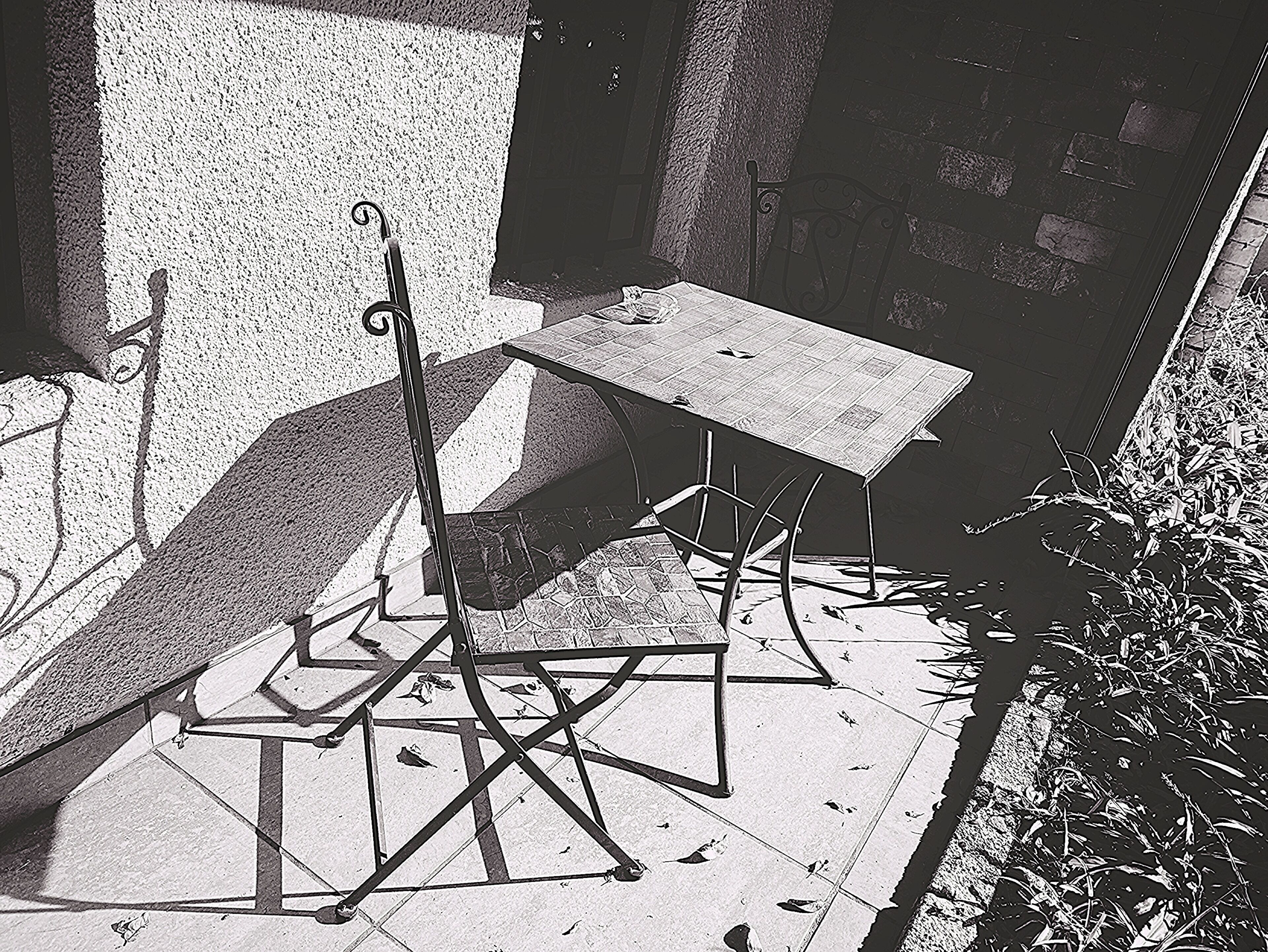 A metal chair and table set outdoors, possibly in a courtyard or patio area.