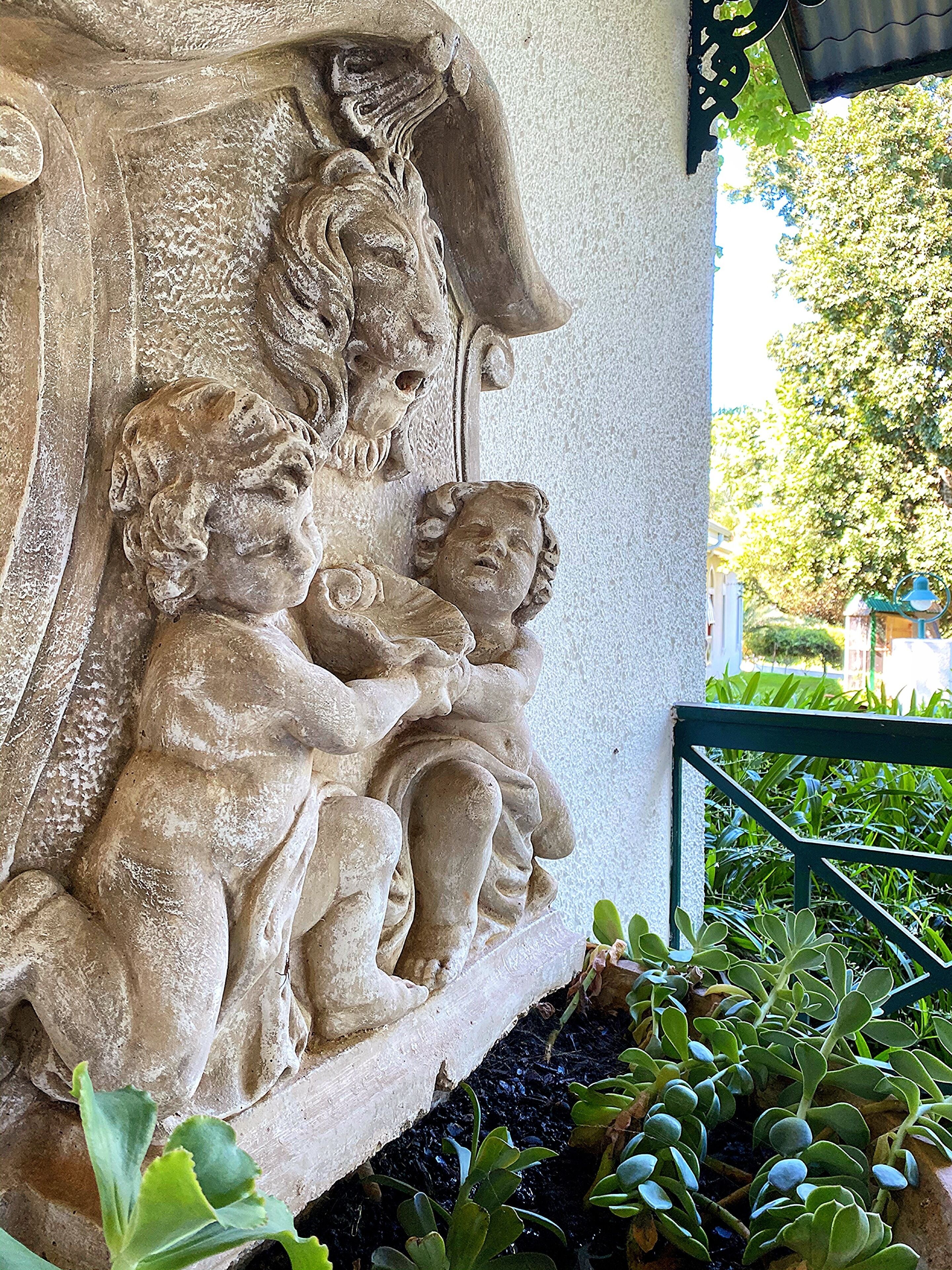 Un relieve pétreo con la representación de tres figuras, posiblemente querubines, en la fachada de un edificio.