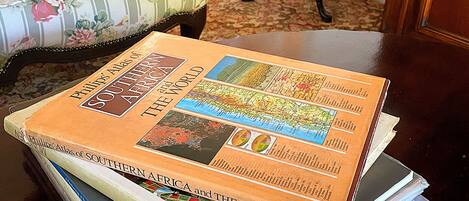 A stack of books titled 'Phillips' Atlas of Southern Africa and the World' on a wooden table.