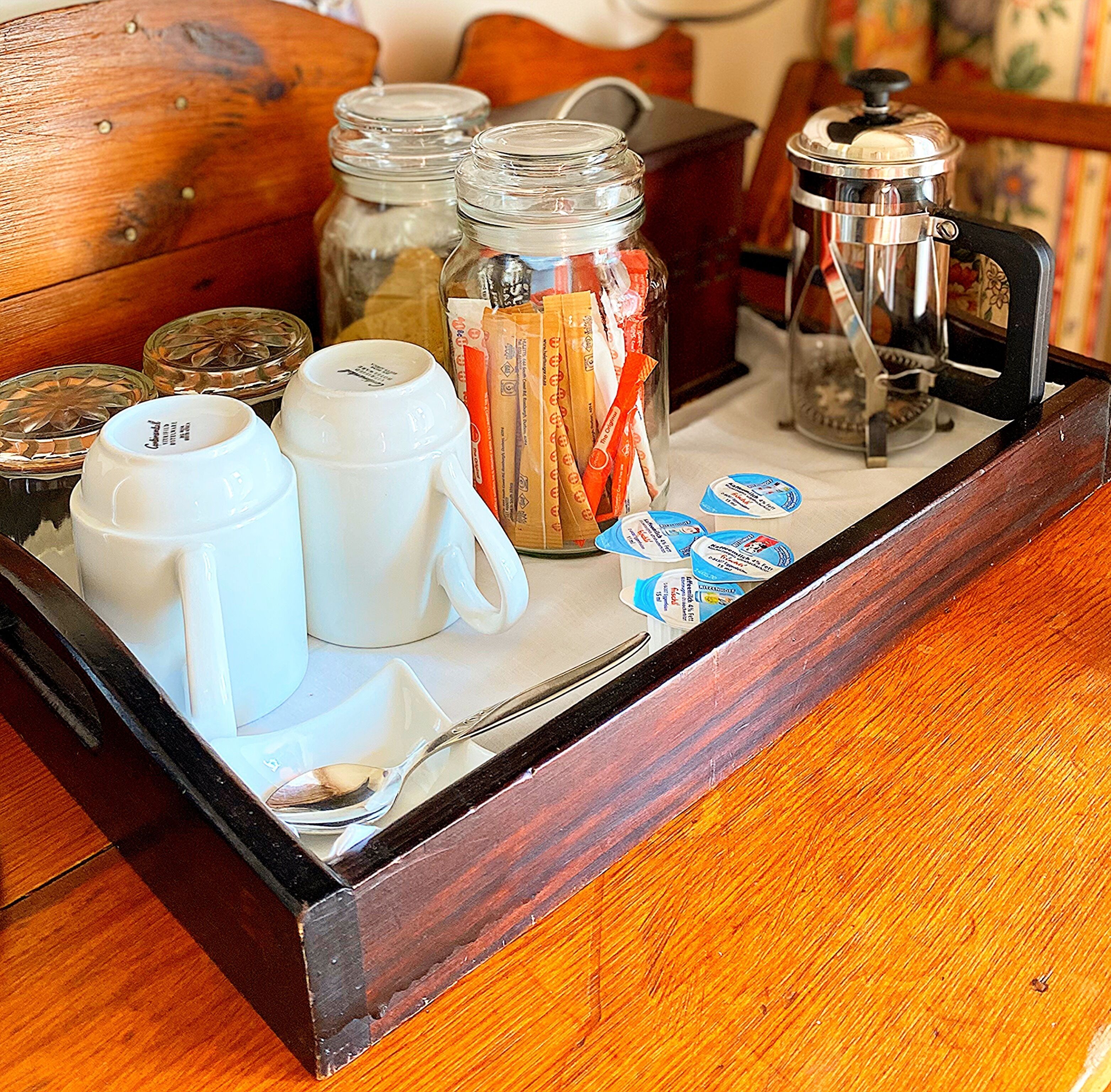 A wooden tray with various breakfast items including coffee, tea, and condiments.