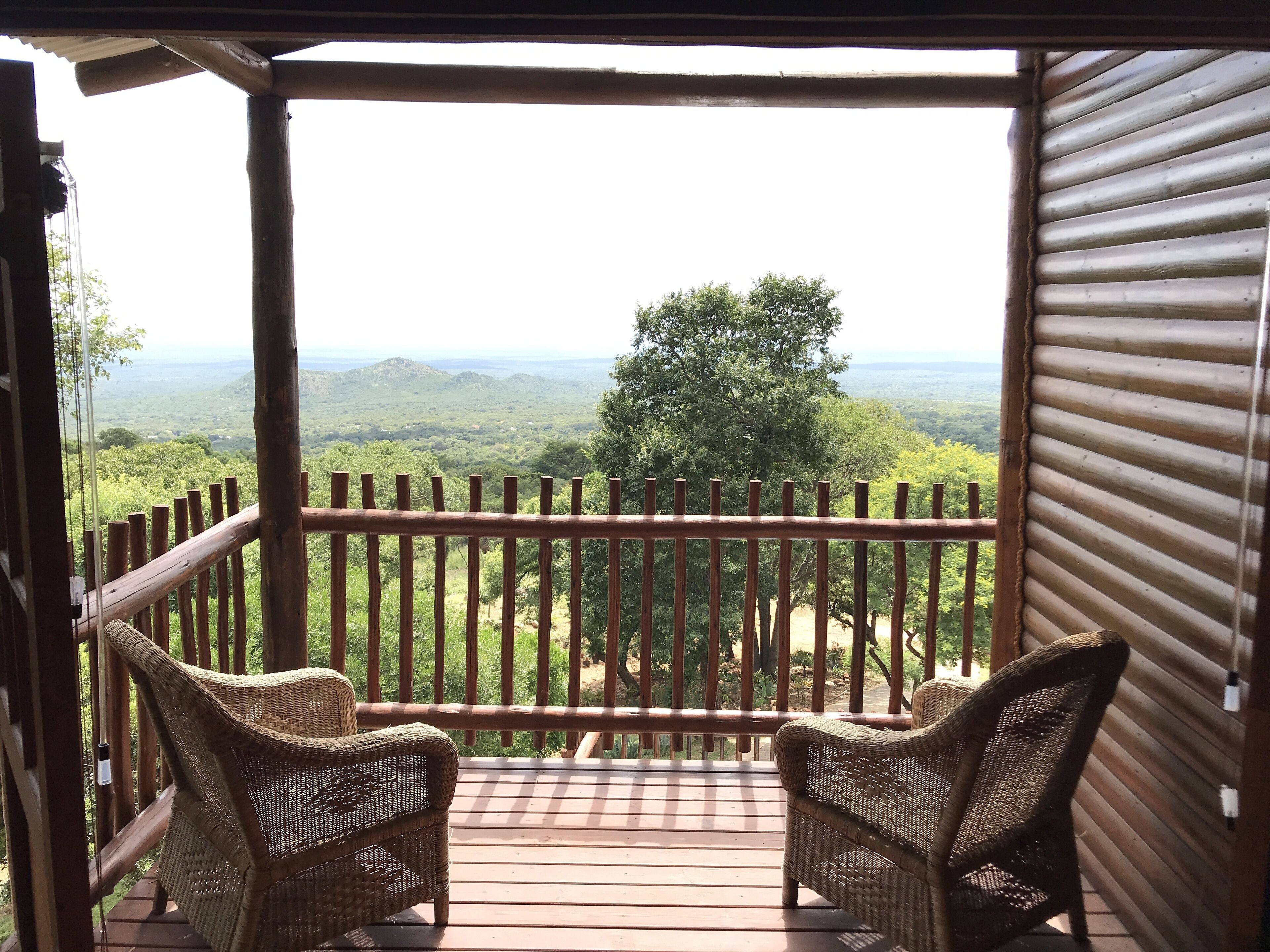 Una terrazza in legno con sedie in vimini che si affaccia su un paesaggio montuoso.