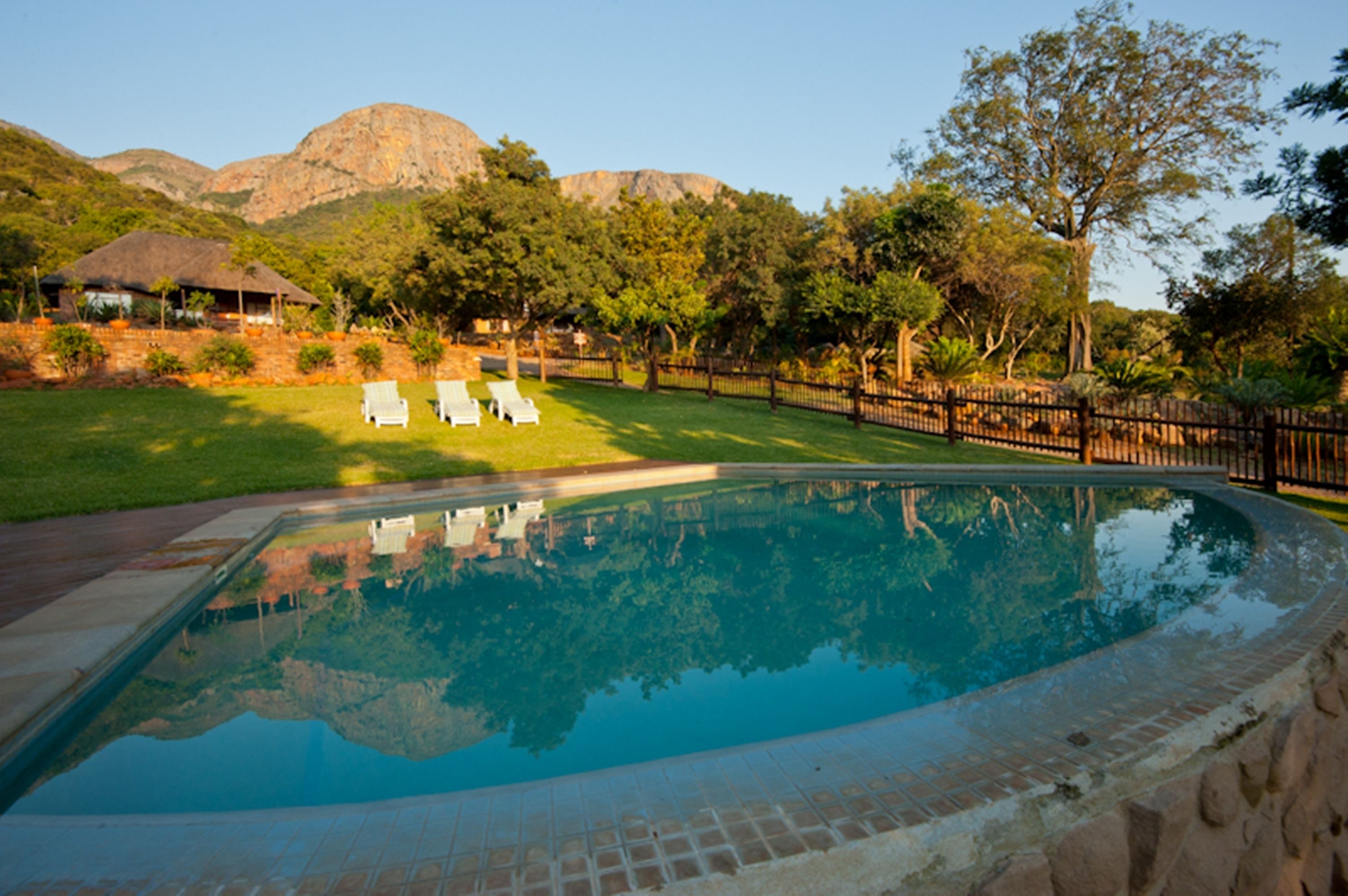 A swimming pool with a clear view of the surrounding landscape, including trees and distant mountains.