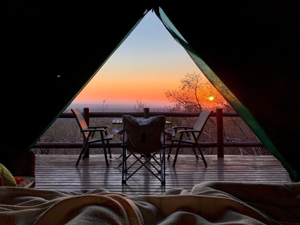 A triangular room with a view of a sunset.