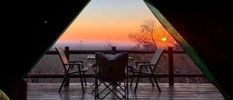 A triangular room with a view of a sunset.