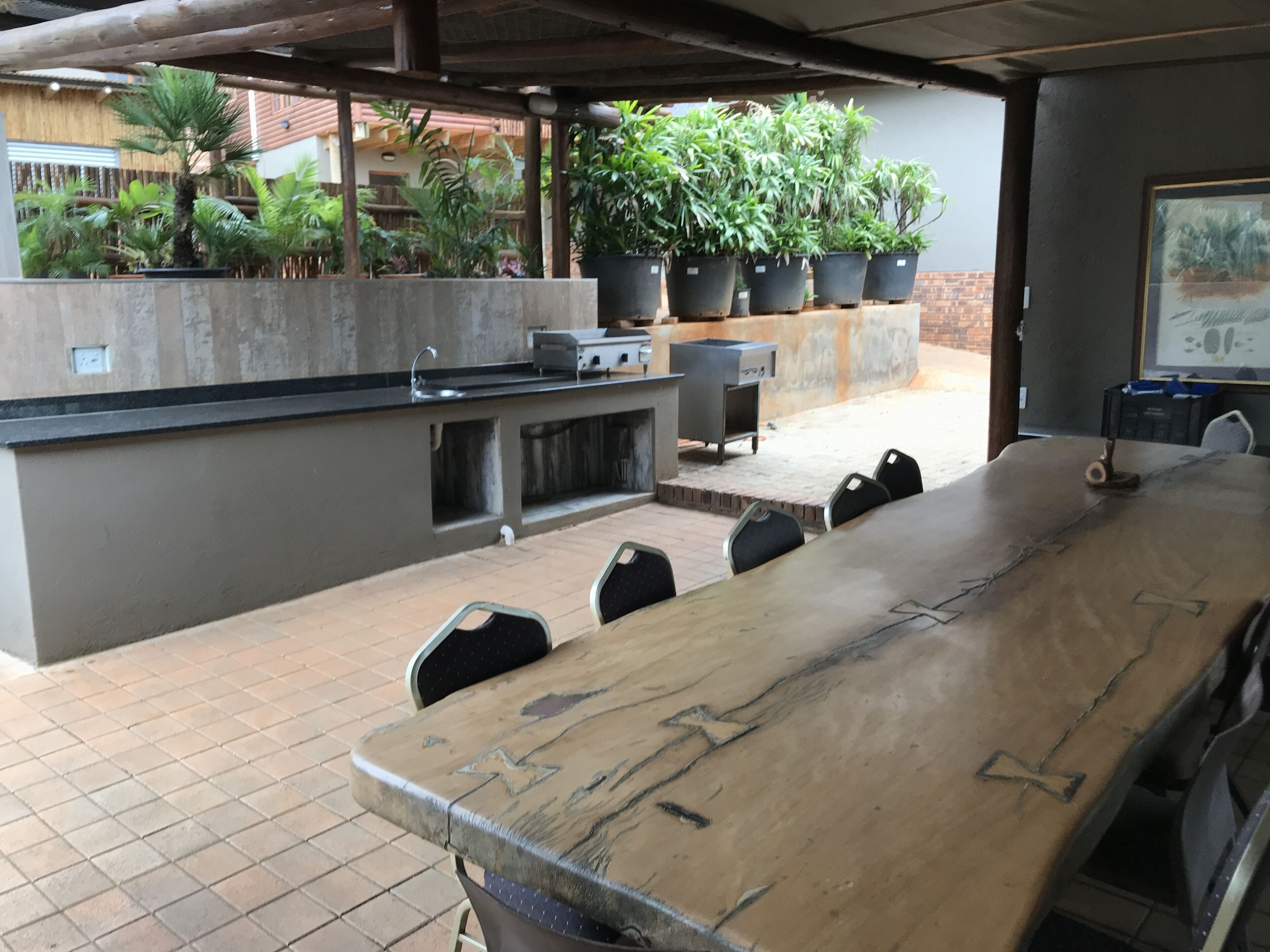 An outdoor bar area with a long counter, several chairs, and a grill station.