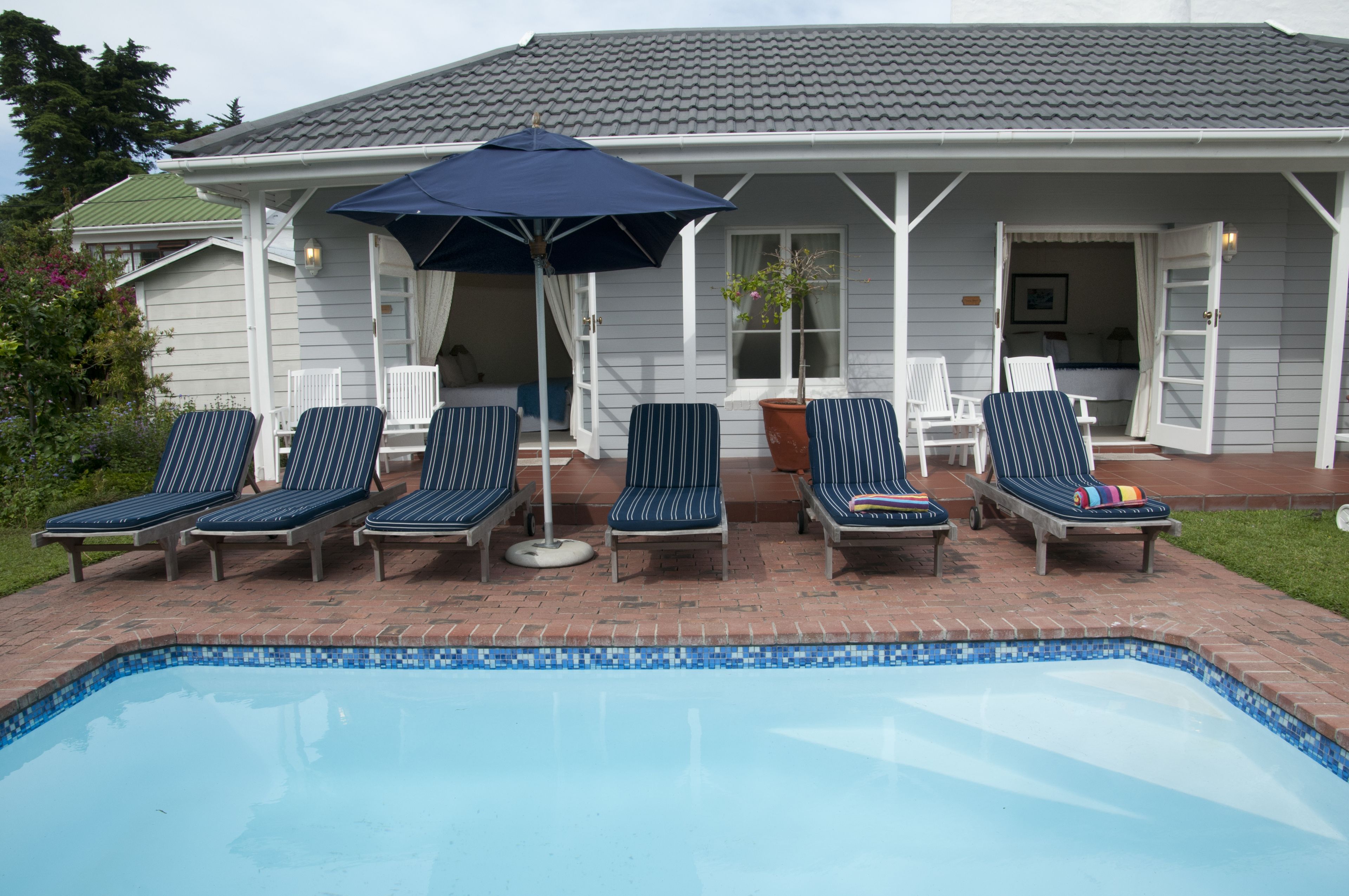 A pool area with lounge chairs and an umbrella.
