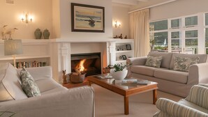 A living room with a fireplace, a sofa, a coffee table, and a bookshelf. - The Knysna Belle (Knysna)