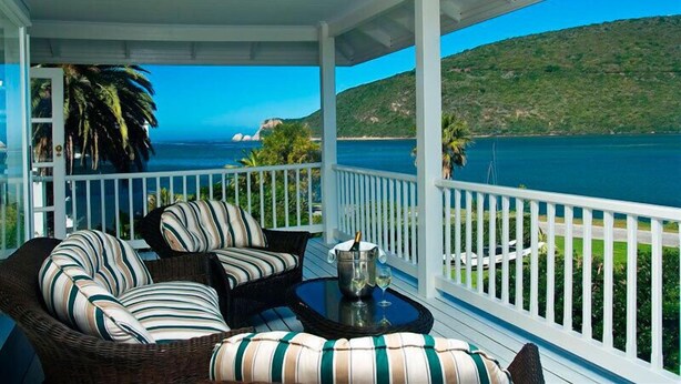 A covered porch with wicker furniture and a view of the ocean. - The Knysna Belle (Knysna)