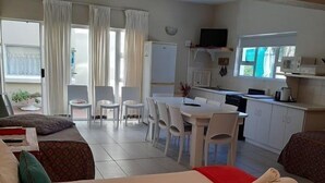 A hotel room with two beds, a dining area, and a kitchenette.