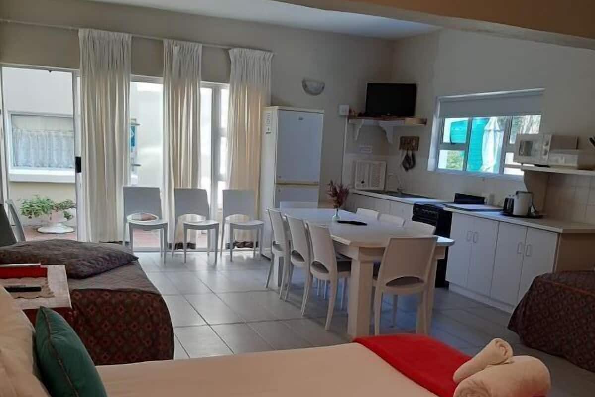 A hotel room with two beds, a dining area, and a kitchenette.