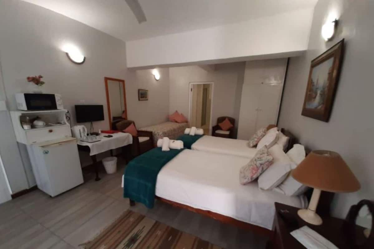 A hotel room with a bed, bedside table, lamp, desk with a computer, and a microwave.
