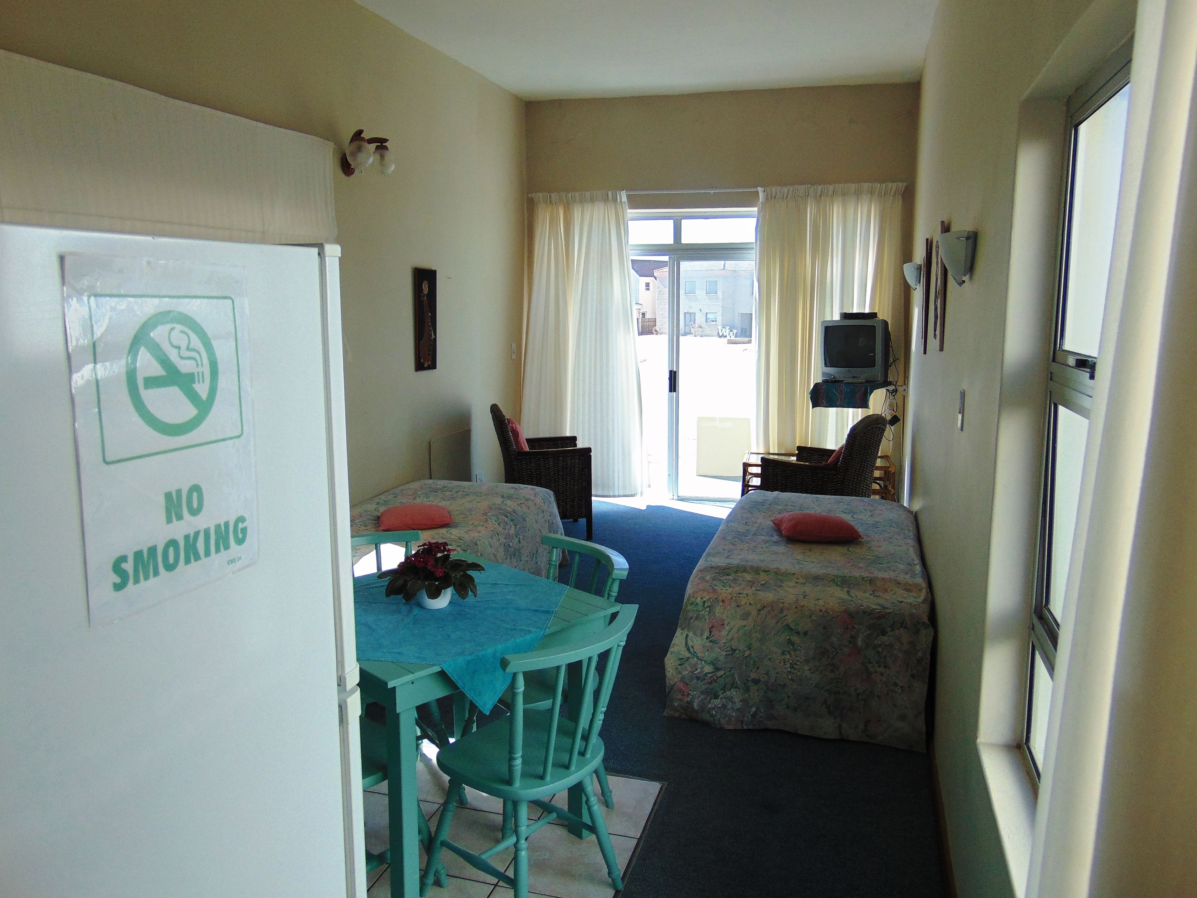 A compact room with a dining table and two single beds.