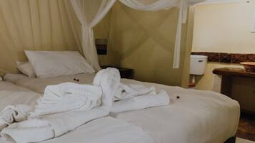 A hotel room with a bed, a nightstand, a bedside table, and a bathroom visible through an open door.