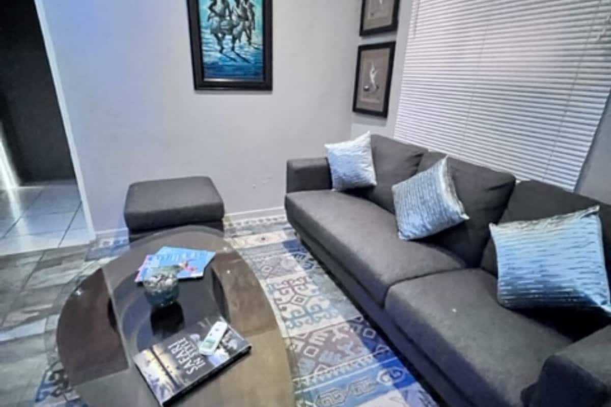 A modern living room with a dark grey sofa, a coffee table, and patterned carpet.