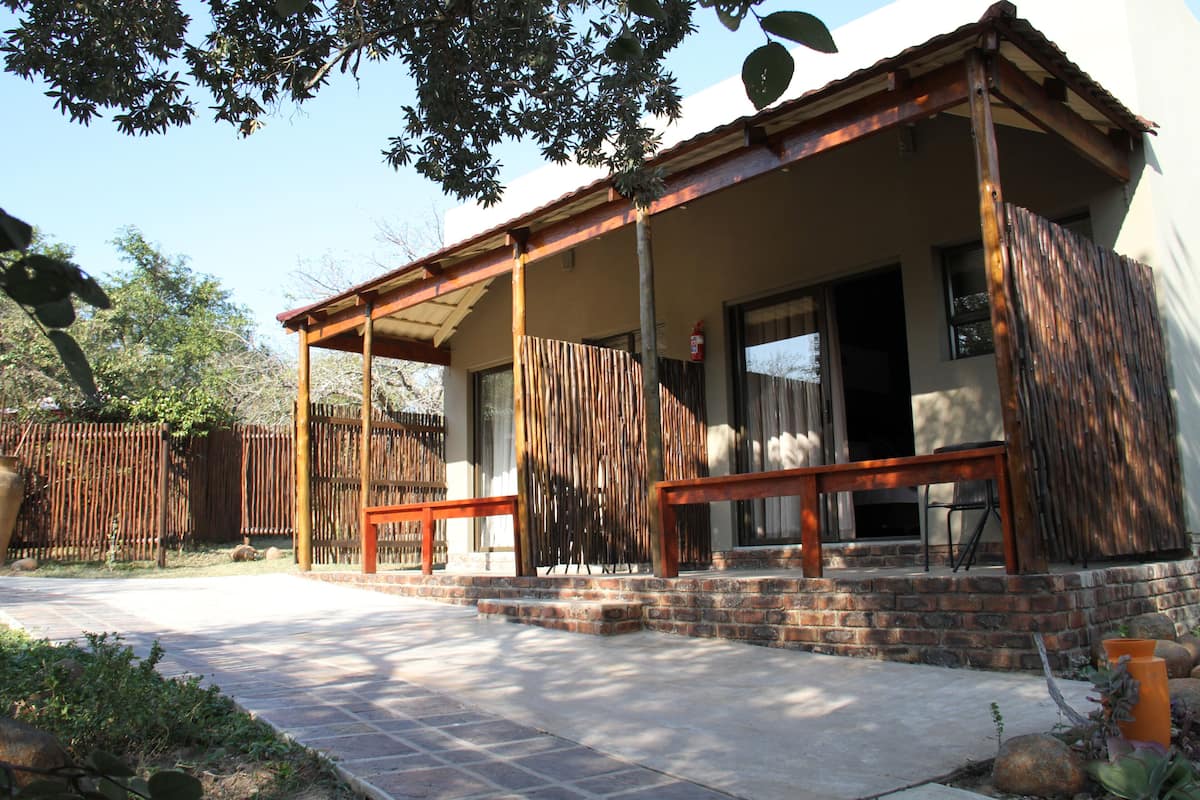 A two-story house with a covered porch, brick steps, and a wooden fence.