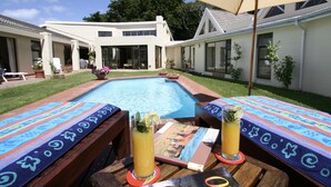Un espace aménagé au bord de la piscine, comprenant une piscine, des chaises longues et un parasol.