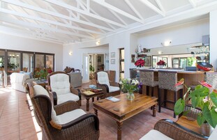 A spacious living area with wicker furniture, a wooden coffee table, and a kitchen in the background.