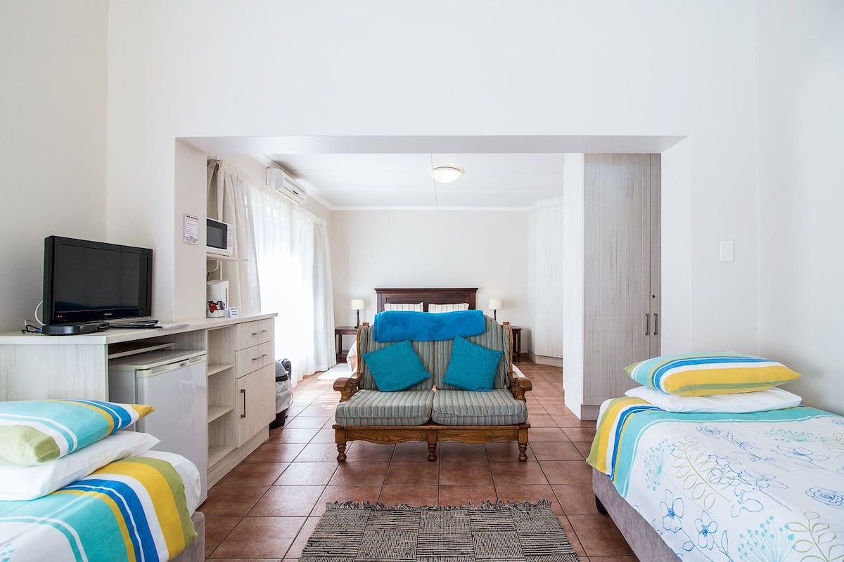 Una habitación de hotel con una cama, una silla, un escritorio con televisor y una mesita.