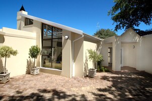 A modern building with a large glass entrance, a brick patio, and potted plants.