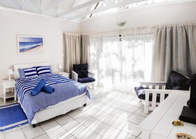 Una habitación de hotel con una cama, una silla, un escritorio y una ventana con cortinas.