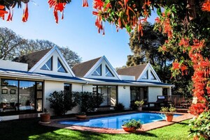 A modern two-story house with a swimming pool, large windows, and a well-maintained garden.