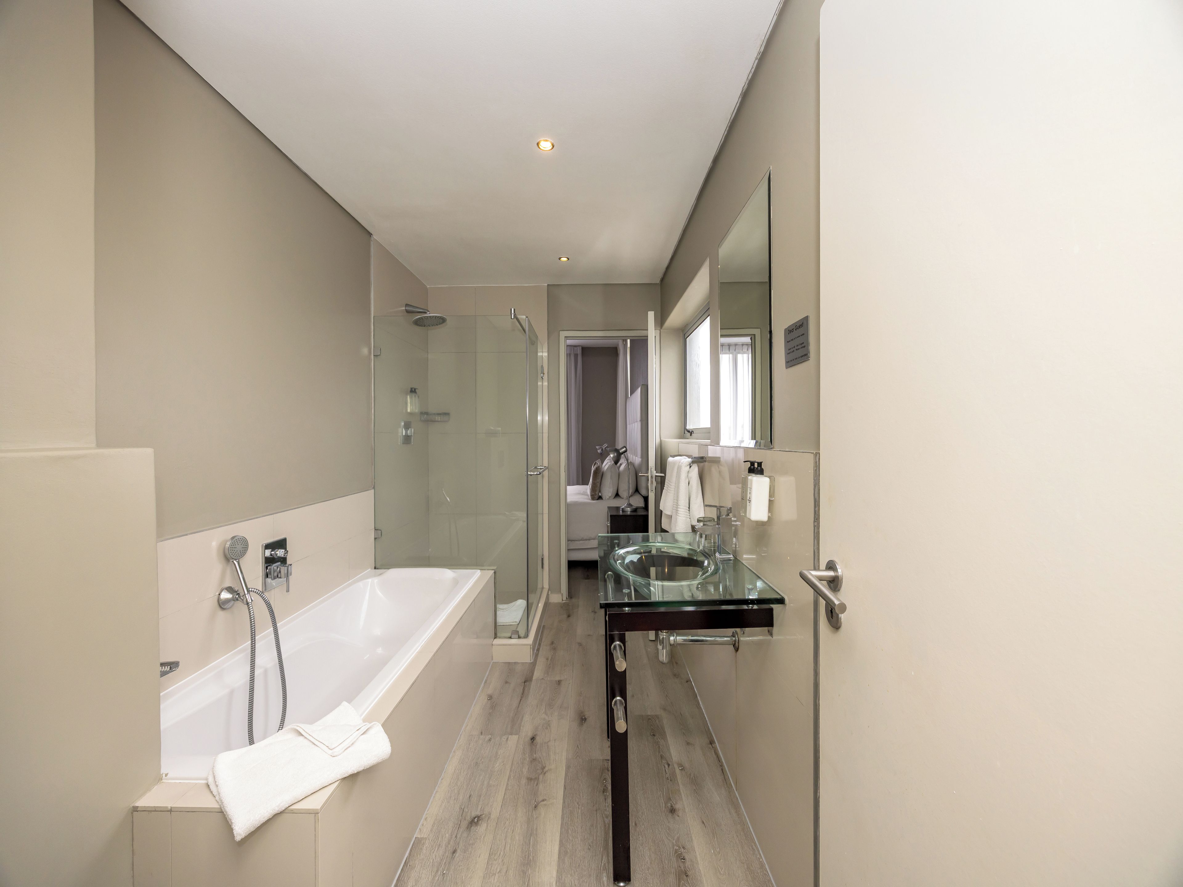 A modern bathroom with a glass-enclosed shower, a freestanding bathtub, and a glass sink.