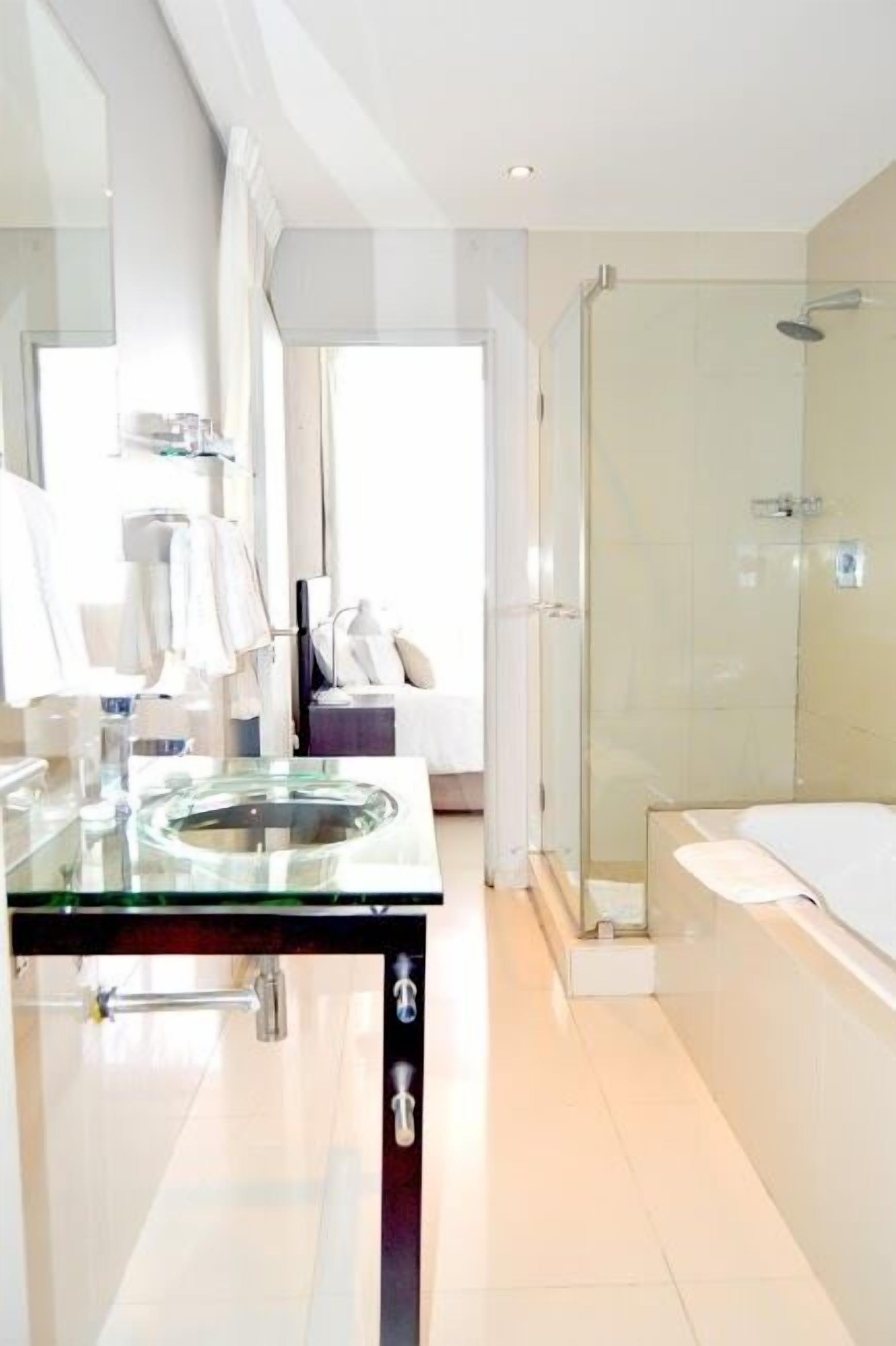 A modern bathroom with a glass sink, a shower, and a bathtub.