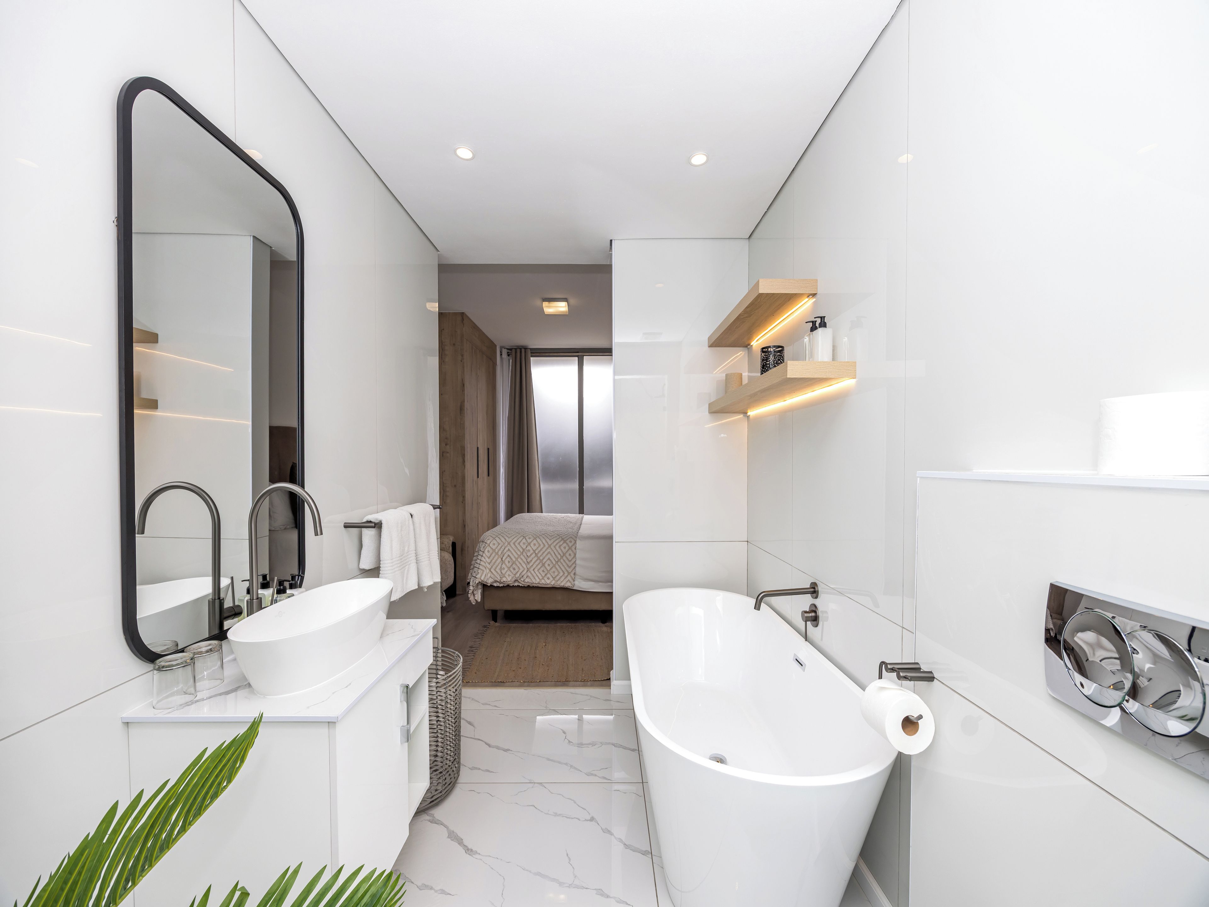 Une salle de bain moderne avec une baignoire sur pieds, un grand miroir et un meuble-lavabo.