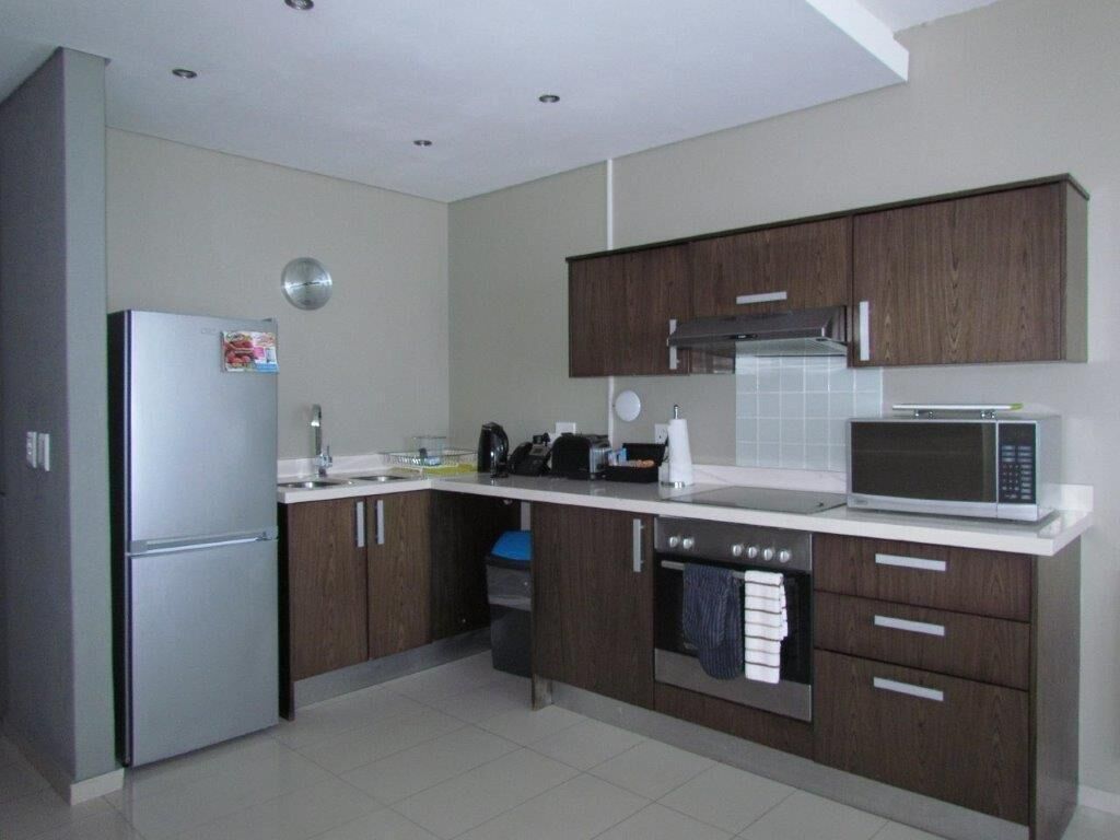 A modern kitchen with a refrigerator, microwave, oven, and wooden cabinets.