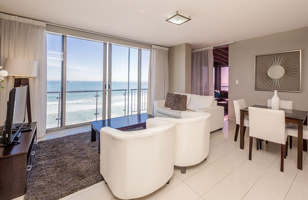 Een moderne hotelkamer met een groot balkon, een eethoek en een televisie.