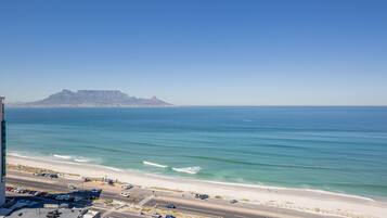 A coastal road with a beach and a mountain in the background.