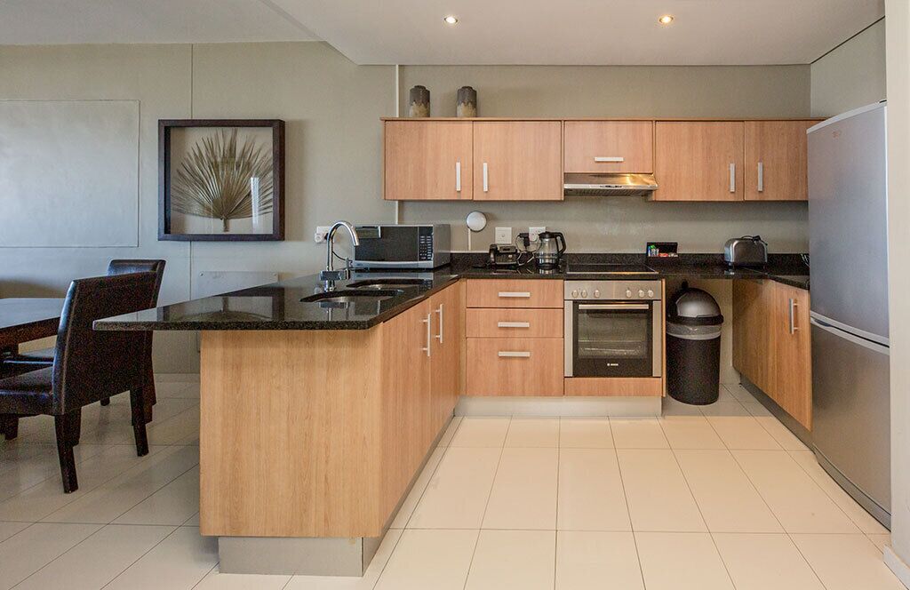 A modern kitchen with wooden cabinets, a central island, a microwave, stove, and a refrigerator.
