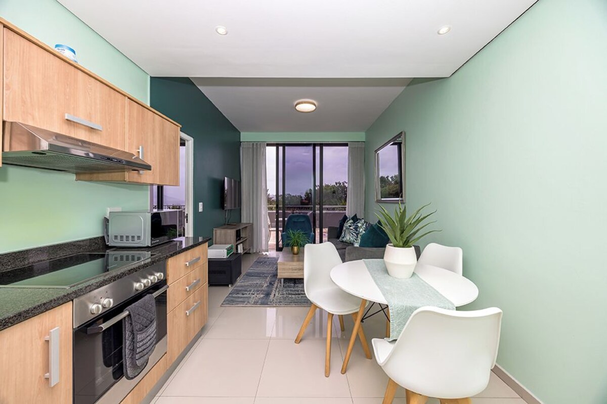 A modern kitchen with a microwave, stove, and cabinets. There is a dining area with a table and chairs.