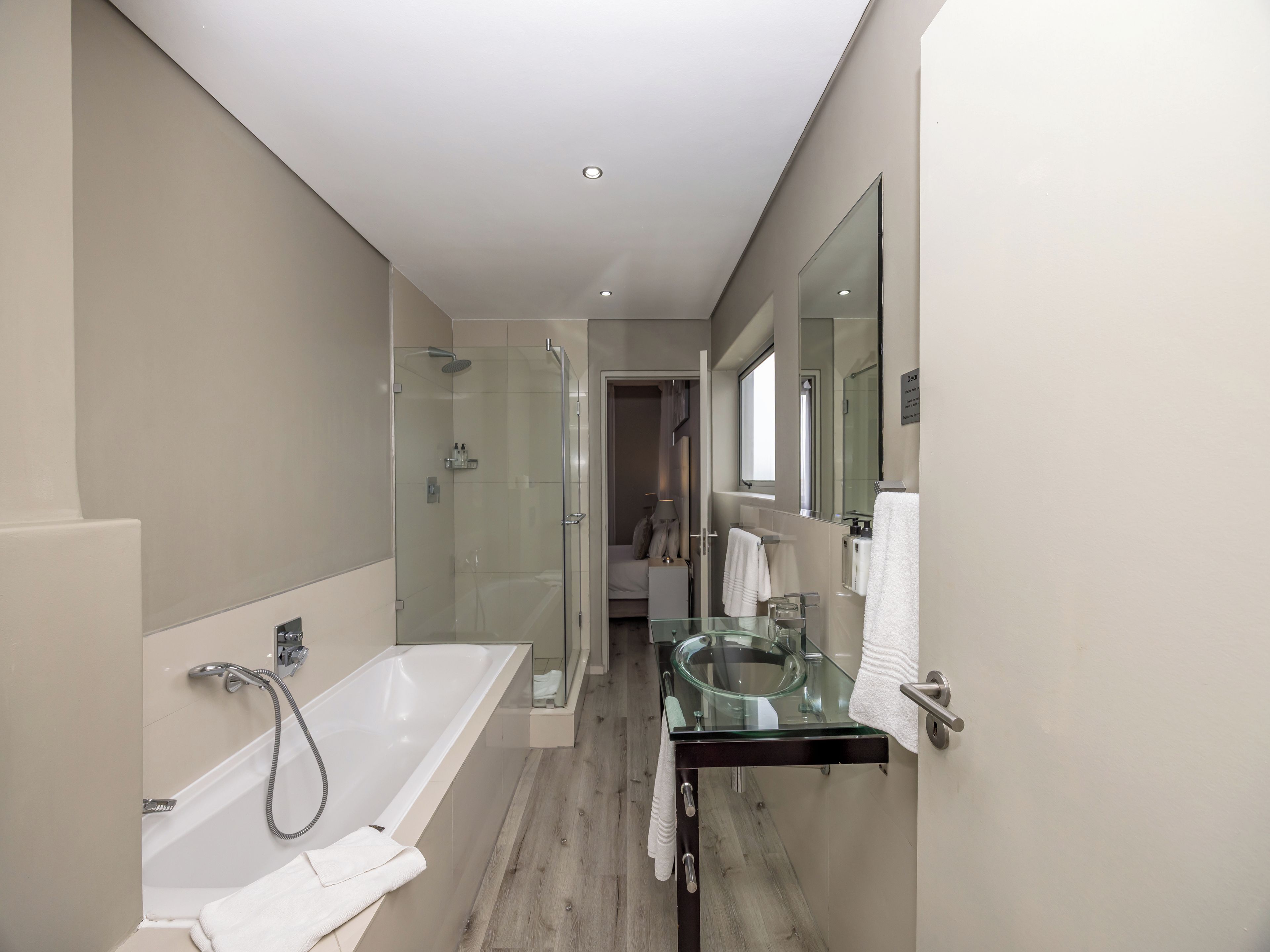 Une salle de bain moderne dotée d’une douche à parois de verre, d’une baignoire sur pieds et d’un meuble-lavabo en verre avec un miroir rond.