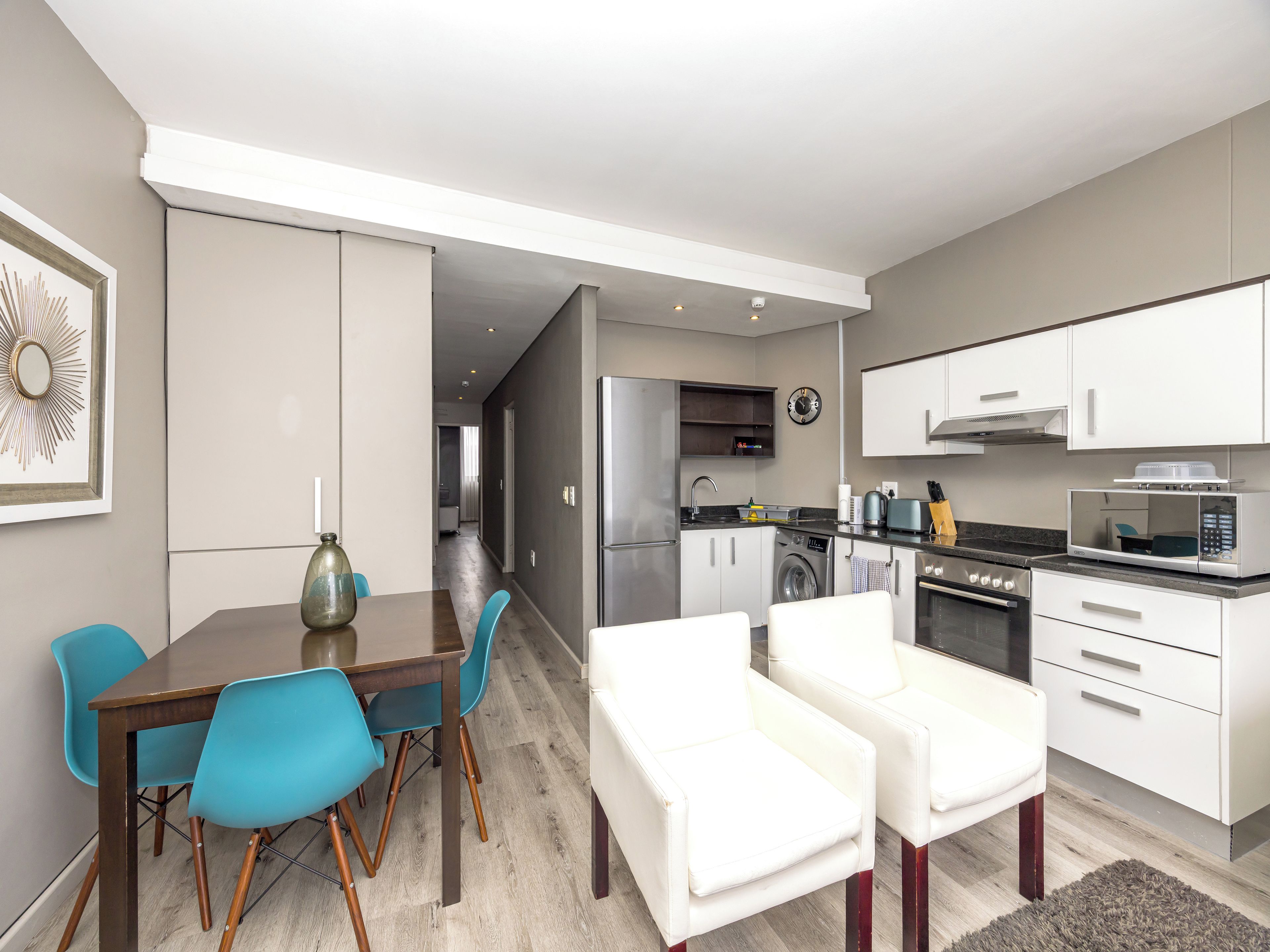 A modern kitchen with white cabinets, a microwave, and a washing machine.