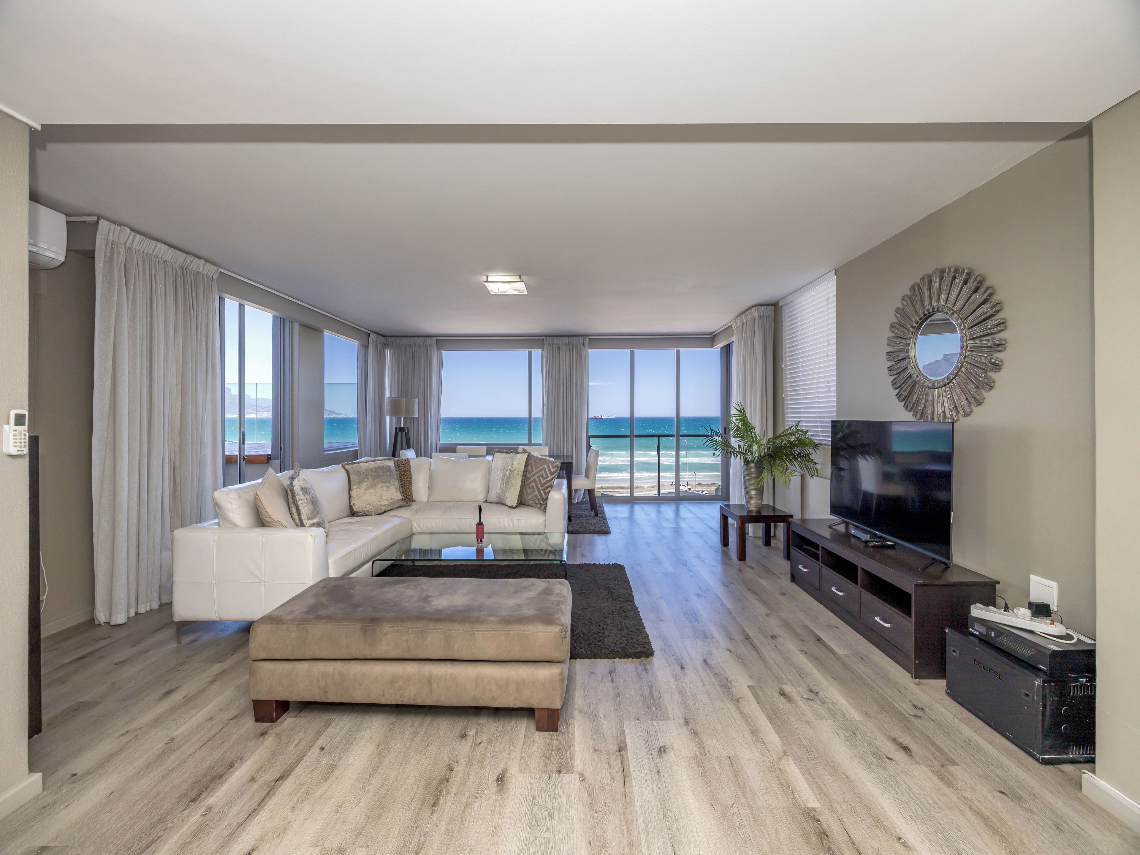 A spacious living room with a large sectional sofa, a flat-screen TV, and a view of the ocean.