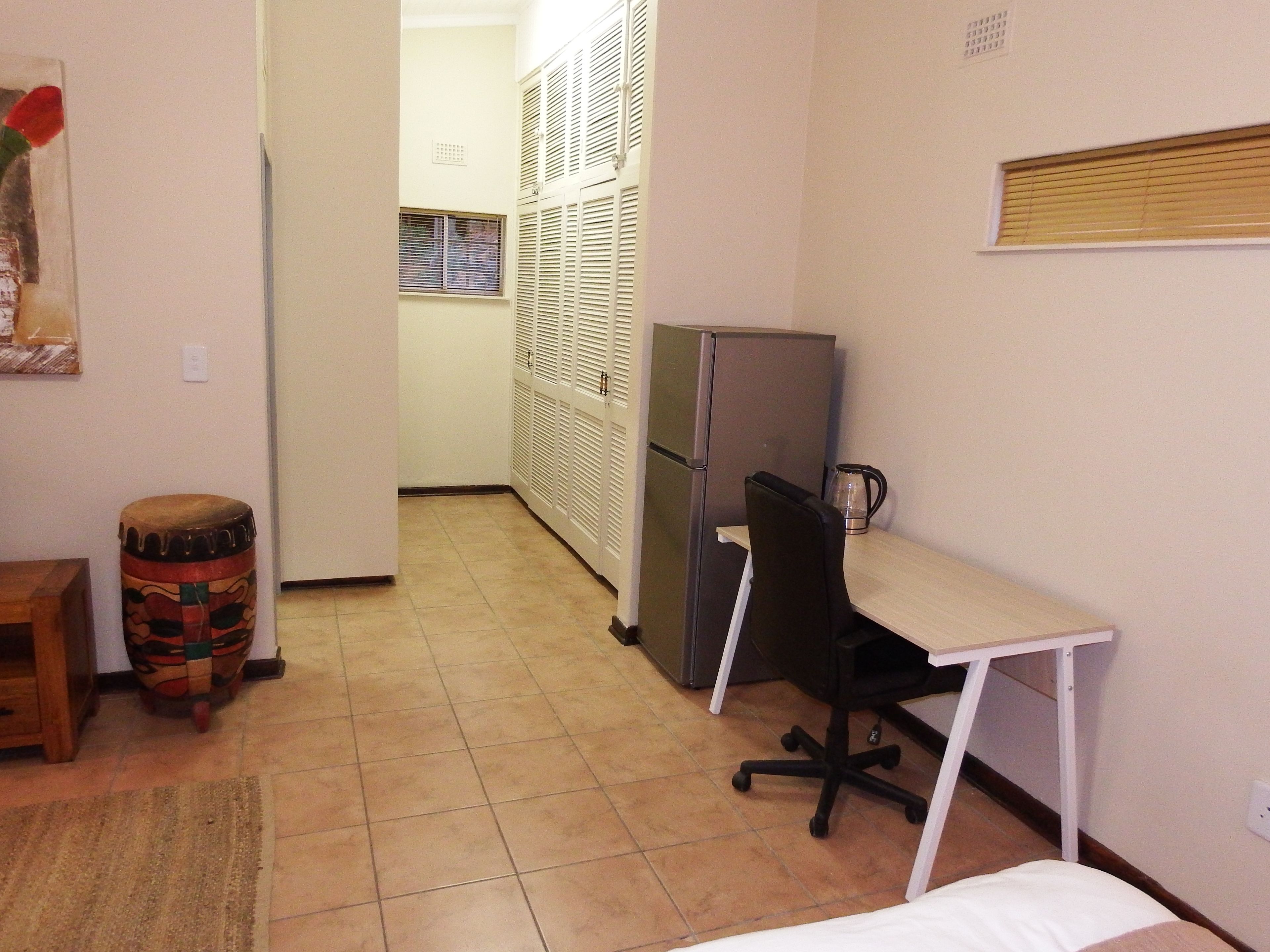 A small, compact room with a kitchenette, a desk, and a chair.
