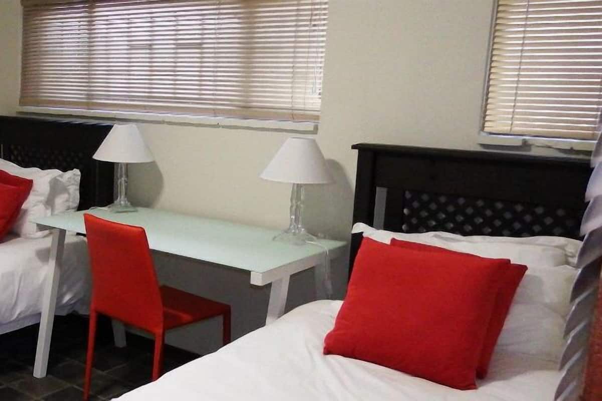A room with two single beds, a desk, and a chair.