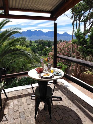 Une table avec des aliments pour le petit-déjeuner, une chaise et une vue sur les montagnes.