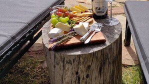 Une table en bois avec une bouteille de vin, un verre, du fromage, des raisins, des crackers et un couteau.