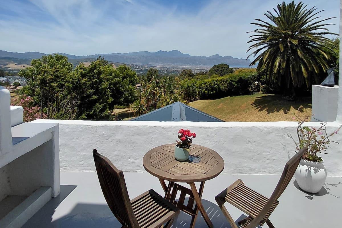 Une terrasse avec une table ronde et deux chaises, d’où l’on peut admirer un paysage de montagnes et de verdure.