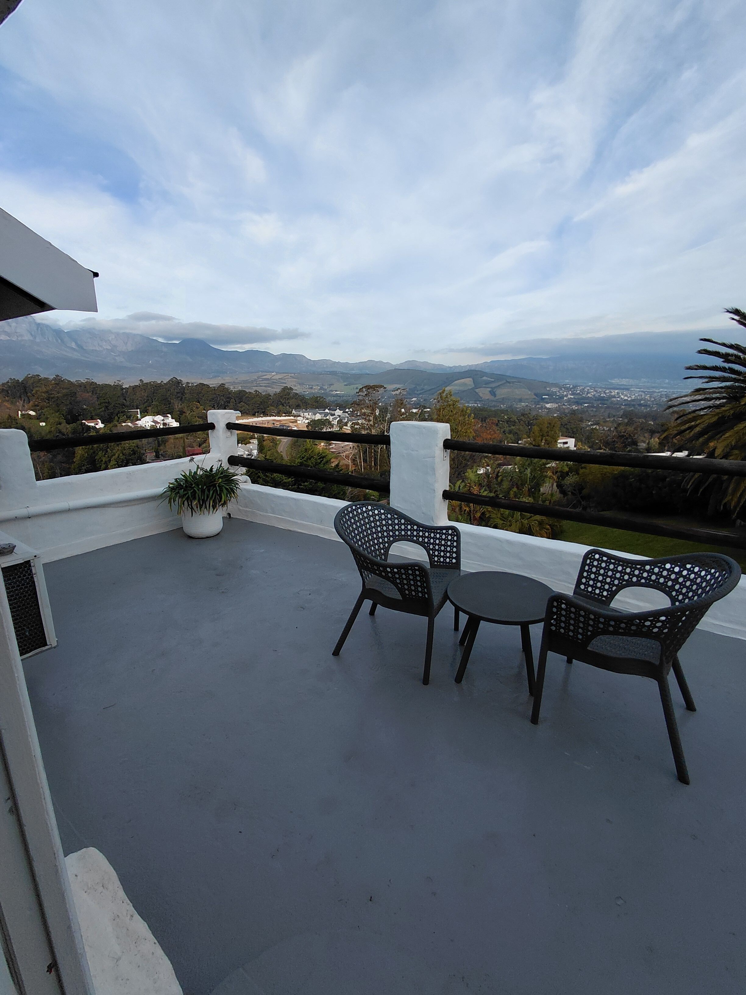 Un balcón con dos sillas y una mesa, con vistas a un paisaje montañoso.