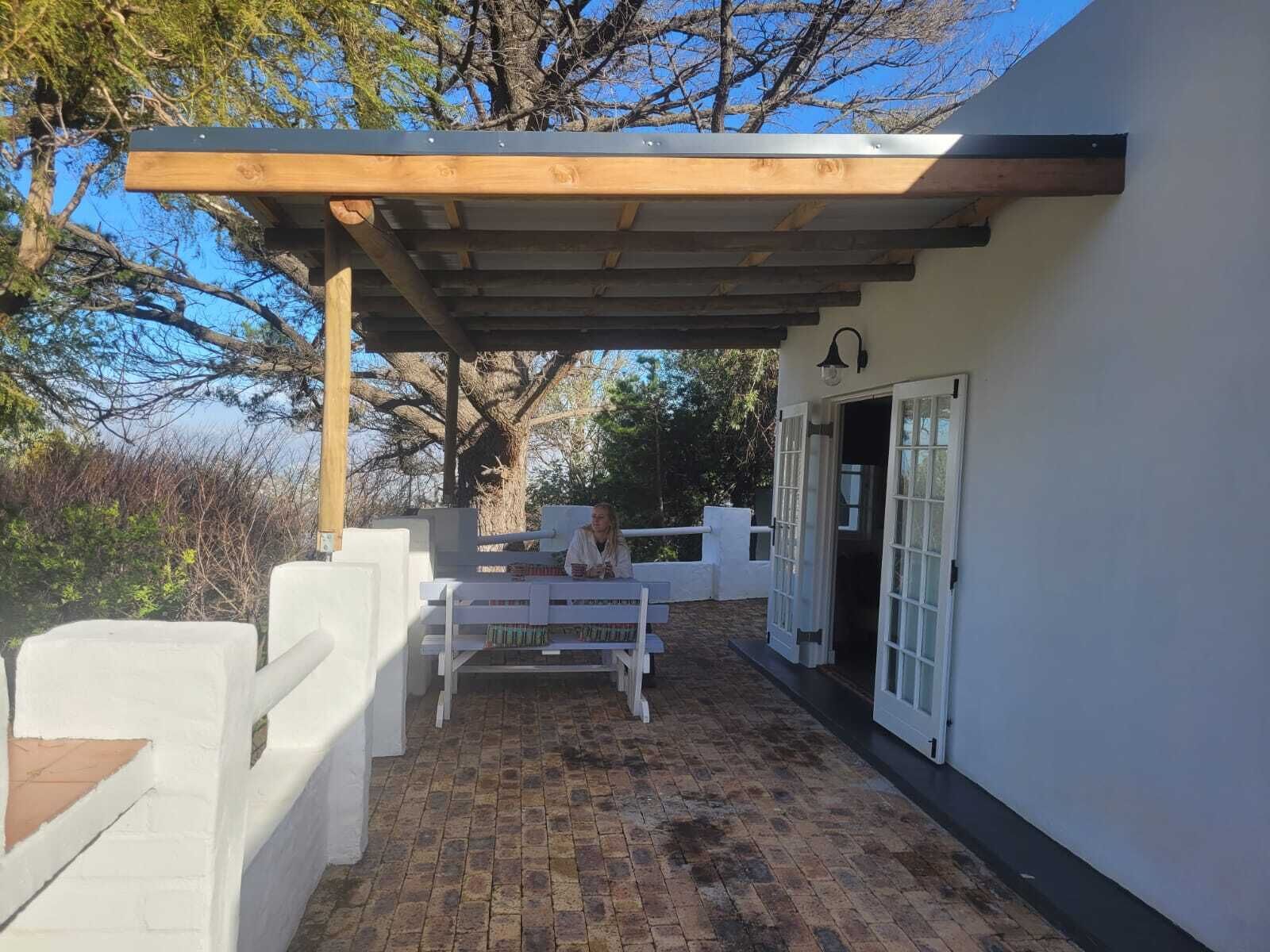 A covered patio with a white fence, a wooden pergola, and a white door with glass panels.