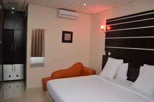 Habitación de hotel con cama, armario, ventana con cortinas y aire acondicionado instalado en la pared.