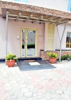 Fachada de piedra, puerta de cristal y porche cubierto en la entrada de un edificio.