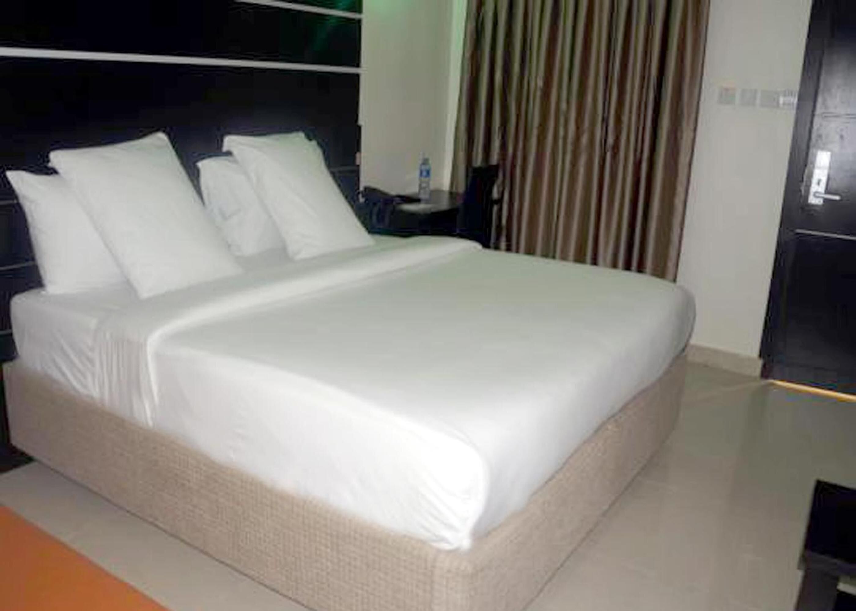 A neatly made bed with white linens in a modern hotel room.