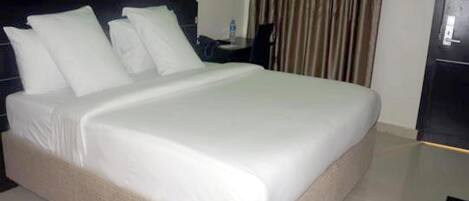 Una cama bien hecha con sábanas blancas en una habitación de hotel moderna.