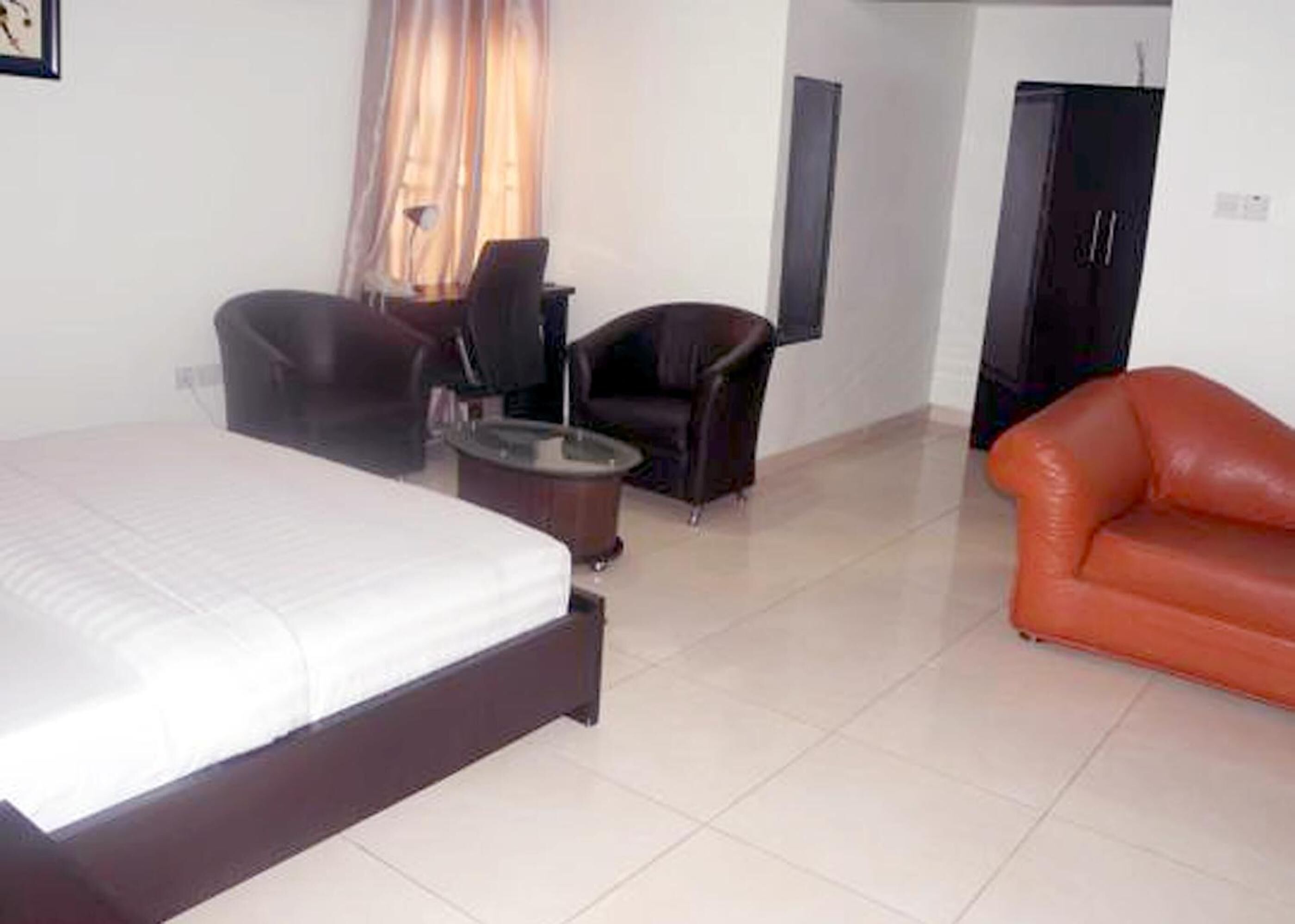 A hotel room with a bed, two armchairs, a small table, and a sofa.