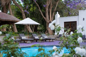 Zona de piscina con sillones de descanso y una sombrilla.
